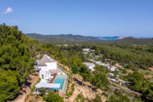 Aerial view of a luxury villa in Es Cubells, Ibiza, featuring stunning sea views, a private pool, and modern architecture.