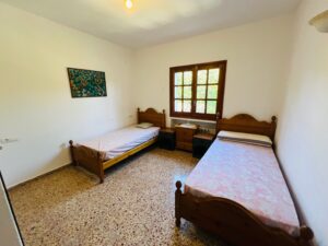 Twin bedroom with Mediterranean style decor and natural lighting.