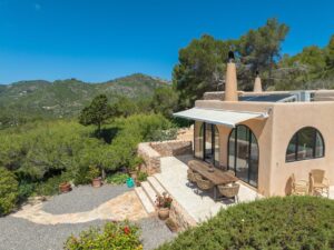 Aerial view of Cana Pedrera: a luxurious villa in Ibiza with a pool, garden and stunning landscapes, captured from a drone.