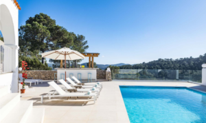 Exterior view of Casa Nashamena in San Miguel, Ibiza, showcasing a private pool, lush gardens, and panoramic views.