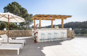 Exterior view of Casa Nashamena in San Miguel, Ibiza, showcasing a private pool, lush gardens, and panoramic views.
