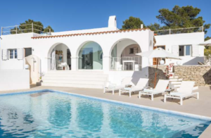 Exterior view of Casa Nashamena in San Miguel, Ibiza, showcasing a private pool, lush gardens, and panoramic views.