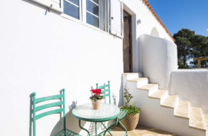 Exterior view of Casa Nashamena in San Miguel, Ibiza, showcasing a private pool, lush gardens, and panoramic views.