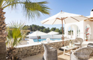 Exterior view of Casa Nashamena in San Miguel, Ibiza, showcasing a private pool, lush gardens, and panoramic views.