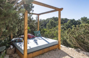 Exterior view of Casa Nashamena in San Miguel, Ibiza, showcasing a private pool, lush gardens, and panoramic views.