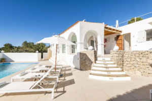 Exterior view of Casa Nashamena in San Miguel, Ibiza, showcasing a private pool, lush gardens, and panoramic views.