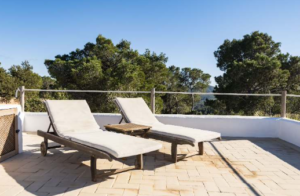 Exterior view of Casa Nashamena in San Miguel, Ibiza, showcasing a private pool, lush gardens, and panoramic views.