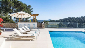 Exterior view of Casa Nashamena in San Miguel, Ibiza, showcasing a private pool, lush gardens, and panoramic views.