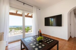 Spacious living room at Luxury Casa Flamenc, Ibiza, featuring a panoramic view, stylish sofa, decorative coffee table, and flat-screen TV.